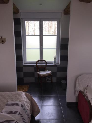 a bedroom with a window and a chair and a bed at La Ferme Pillet in Berville