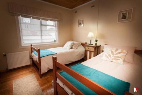 1 dormitorio con 2 camas y ventana en Innata Casa Hostal, en Punta Arenas