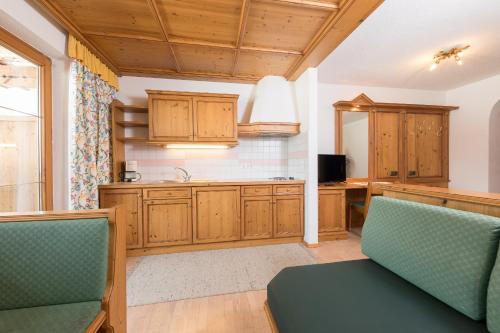 a kitchen with wooden cabinets and green chairs at Pension Margretenhof in Fulpmes
