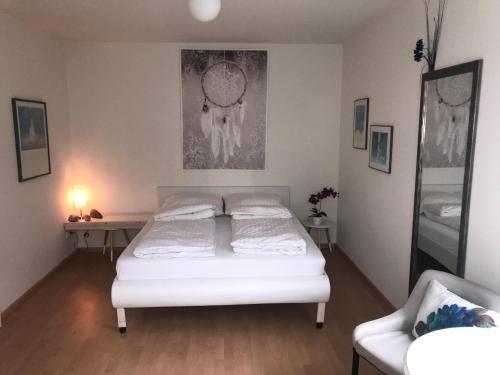 a bedroom with a white bed and a chair at Gästezimmer am Oos Bach in Baden-Baden