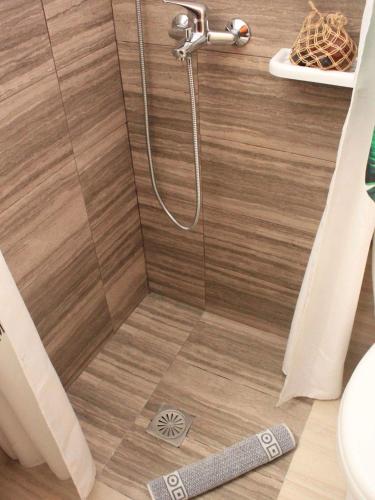 a shower in a bathroom with a wooden floor at Kotroni studios in Skiathos