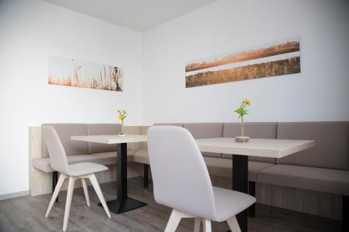 two white chairs and a table in a restaurant at Gästehaus Pusztablick in Illmitz