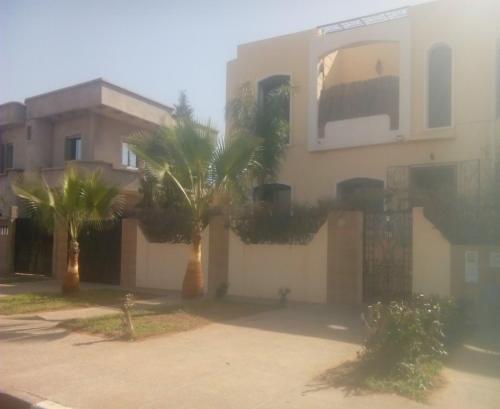 a building with two palm trees in front of it at Draga, Agadir appart et piscine dans villa, in Cite Adrar