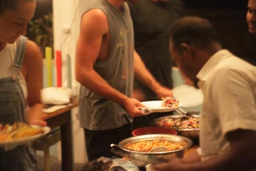 a group of people standing around plates of food at Arne's Place in Arugam Bay