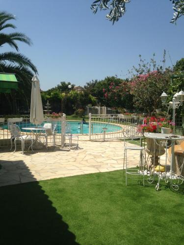 a swimming pool with chairs and a table and a umbrella at Charmant Studio à Uchaud in Uchaud