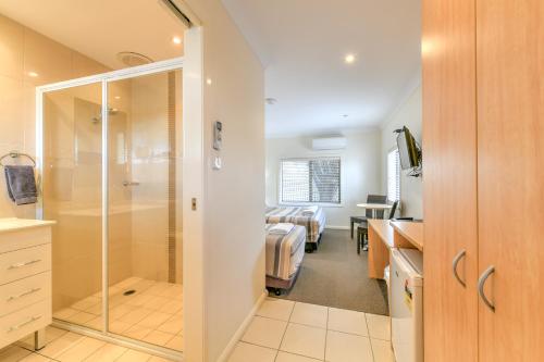 a bathroom with a shower and a bedroom at Motel Grande in Tamworth