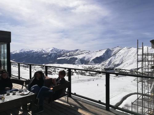 a group of people sitting on a deck with mountains in the background at Apartment N503 Gudauri Loft in Gudauri