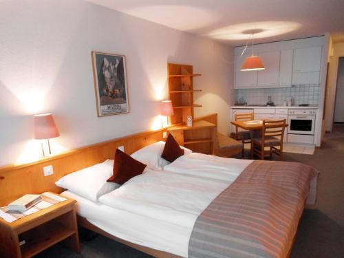 a bedroom with a large white bed and a kitchen at Hotel Aeschipark in Aeschi