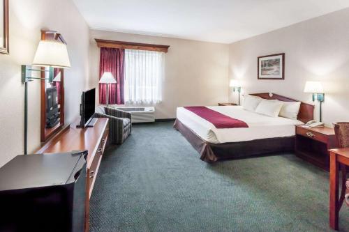 a hotel room with a bed and a television at Baymont by Wyndham New Buffalo in New Buffalo