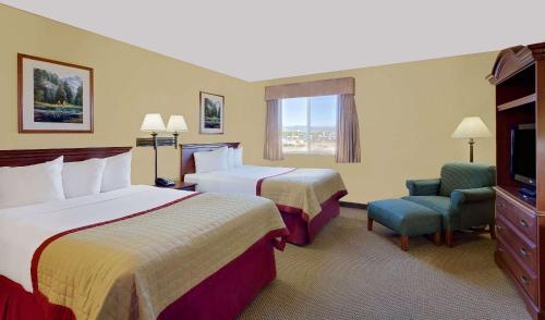 Cette chambre comprend deux lits et une télévision. dans l'établissement Pinedale Hotel & Suites, à Pinedale