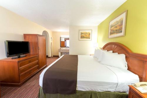 a hotel room with a bed and a flat screen tv at Baymont by Wyndham Louisville East in Louisville