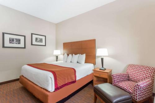 a hotel room with a bed and a chair at Baymont by Wyndham Savannah/Garden City in Savannah