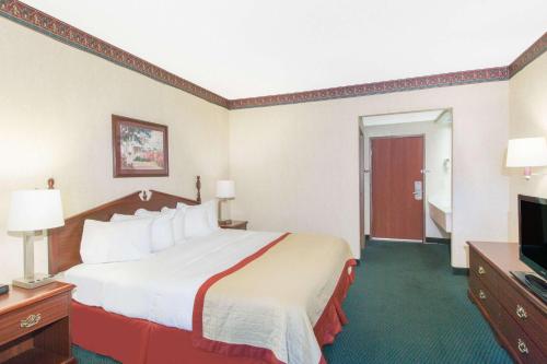 a hotel room with a large bed and a flat screen tv at Baymont by Wyndham Jonesboro in Jonesboro