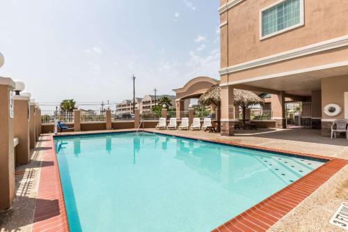 een zwembad in een hotel met een gebouw bij Baymont by Wyndham Galveston in Galveston
