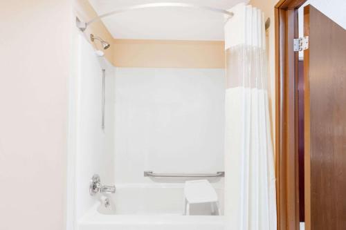 a bathroom with a white shower curtain and a toilet at Baymont by Wyndham Kalamazoo West in Kalamazoo