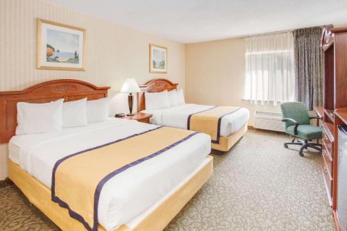 a hotel room with two beds and a television at Baymont by Wyndham Kalamazoo West in Kalamazoo