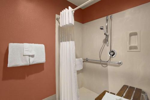 baño con ducha con cortina blanca en Baymont by Wyndham Sullivan, en Sullivan