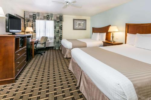 Una habitación de hotel con dos camas y un televisor de pantalla plana. en Baymont by Wyndham Arlington At Six Flags Dr, en Arlington