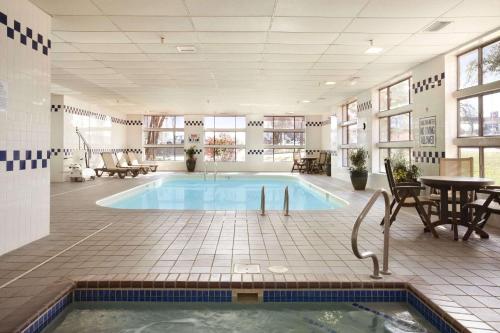 a large swimming pool in a room with a table and chairs at Baymont by Wyndham Sioux Falls in Sioux Falls