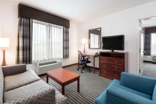 a living room with a couch and a tv and a desk at Baymont by Wyndham Denver International Airport in Denver