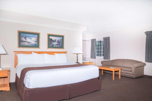 a hotel room with a large bed and a chair at Baymont by Wyndham Baxter/Brainerd Area in Baxter