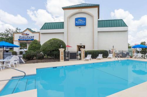 einem Pool vor einem Hotel mit einem Gebäude in der Unterkunft Baymont by Wyndham Greensboro/Coliseum in Greensboro