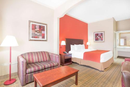 a hotel room with a bed and a chair at Baymont by Wyndham Crestview in Crestview