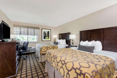 a hotel room with two beds and a flat screen tv at Baymont by Wyndham Erie in Erie
