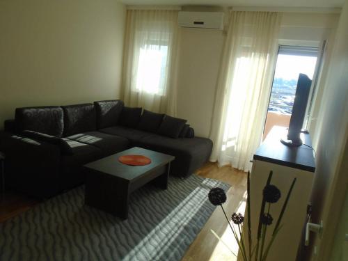 een woonkamer met een zwarte bank en een tafel bij Fantastic brand new apartment in Podgorica
