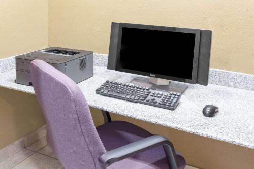 a computer sitting on a desk with a purple chair at Baymont by Wyndham Fort Wayne in Fort Wayne