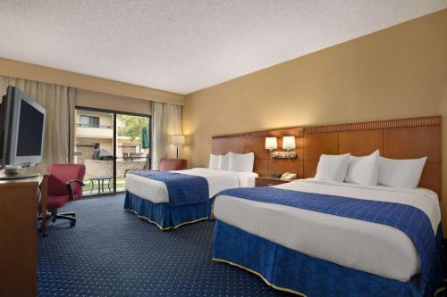 Cette chambre comprend deux lits et une télévision. dans l'établissement Baymont by Wyndham Columbia Northwest, à Columbia