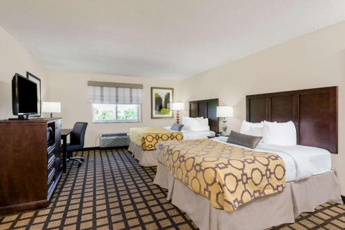 a hotel room with two beds and a flat screen tv at Baymont by Wyndham Erie in Erie