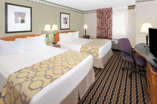 a hotel room with two beds and a desk at Baymont by Wyndham Fort Wayne in Fort Wayne