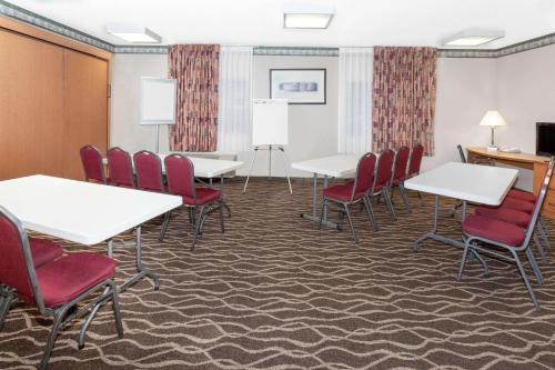 a conference room with white tables and red chairs at Baymont by Wyndham Fort Wayne in Fort Wayne