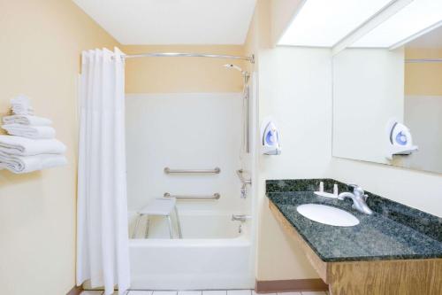 bagno con vasca, lavandino e doccia di Baymont by Wyndham Ozark a Ozark