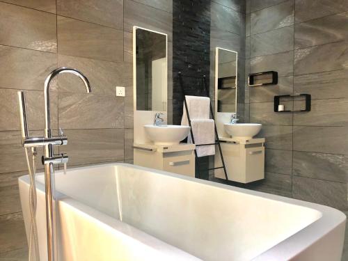 baño con bañera blanca grande y 2 lavabos en Amber Villas Diani, en Diani Beach