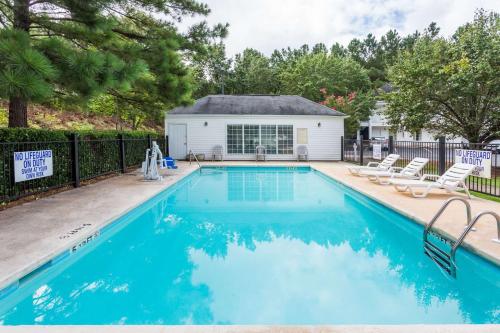a swimming pool with chairs and a house at Baymont by Wyndham Greenwood in Greenwood