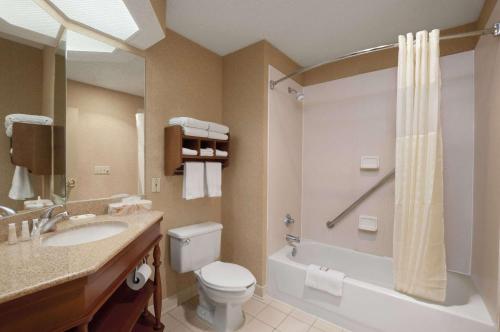 a bathroom with a toilet and a sink and a shower at Baymont by Wyndham Lewisville in Lewisville