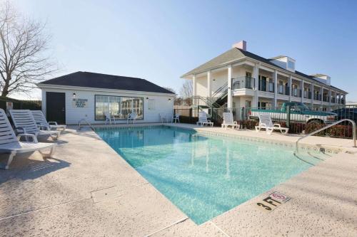 a swimming pool with chairs and a house at Baymont by Wyndham Gaffney in Gaffney