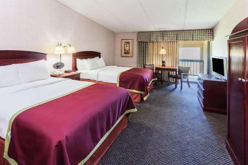 a hotel room with two beds and a desk at Baymont by Wyndham Michigan City in Michigan City