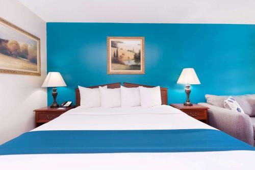 a bed in a hotel room with a blue wall at Baymont by Wyndham Duncan/Spartanburg in Duncan