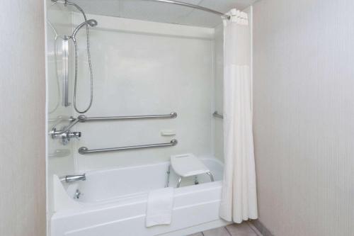 a bathroom with a shower and a white bath tub at Baymont by Wyndham Michigan City in Michigan City