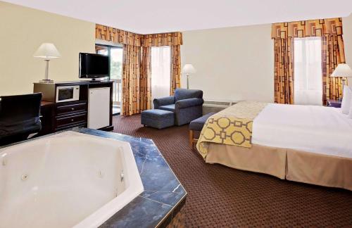 a hotel room with a bed and a bath tub at Baymont by Wyndham Battle Creek Downtown in Battle Creek
