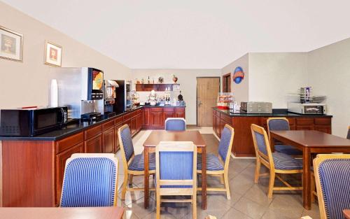 a restaurant with a table and chairs and a kitchen at Baymont by Wyndham Battle Creek Downtown in Battle Creek