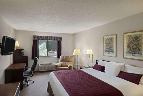 a hotel room with a large bed and a desk at Baymont by Wyndham Whitewater in Whitewater