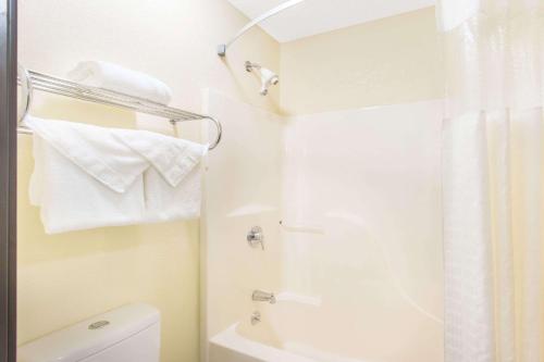 a bathroom with a shower and a toilet and towels at Baymont by Wyndham Muskegon in Muskegon