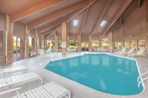 a swimming pool in a building with chairs and tables at Baymont by Wyndham Port Huron in Port Huron