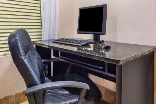 a desk with a computer monitor and a chair at Baymont by Wyndham Cornelia in Cornelia
