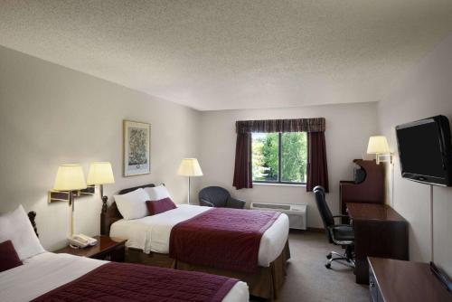 a hotel room with two beds and a flat screen tv at Baymont by Wyndham Whitewater in Whitewater