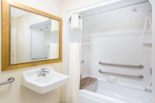 a bathroom with a sink, mirror and bath tub at Baymont by Wyndham Muskegon in Muskegon